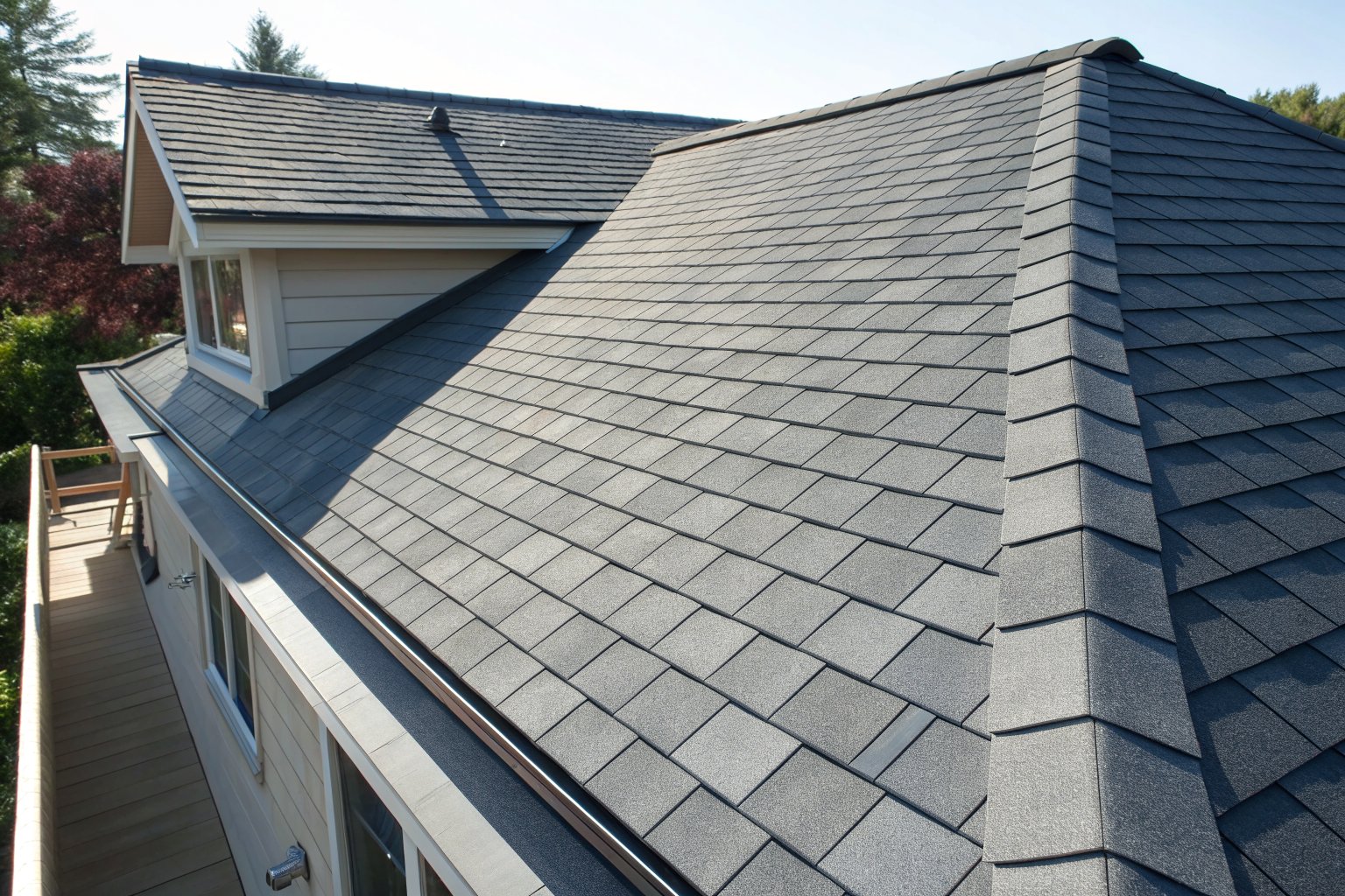 New charcoal-gray architectural shingles and a ridge cap in bright sun